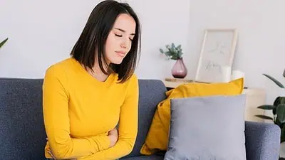 Empathetic woman clutching her stomach, representing women's health and OB-GYN services.