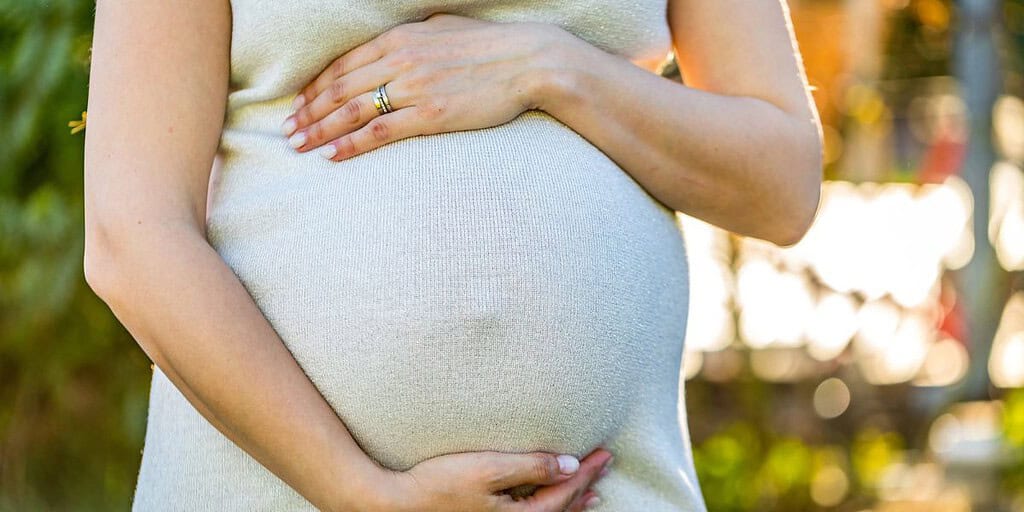 Pregnant woman gently cradling her belly, symbolizing maternal health and awareness in stillbirth prevention discussions.